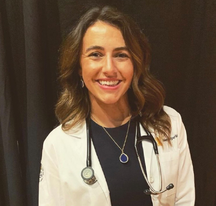 Christina Gibbs, Medical student casual headshot in white dr. coat and stethoscope around her neck.